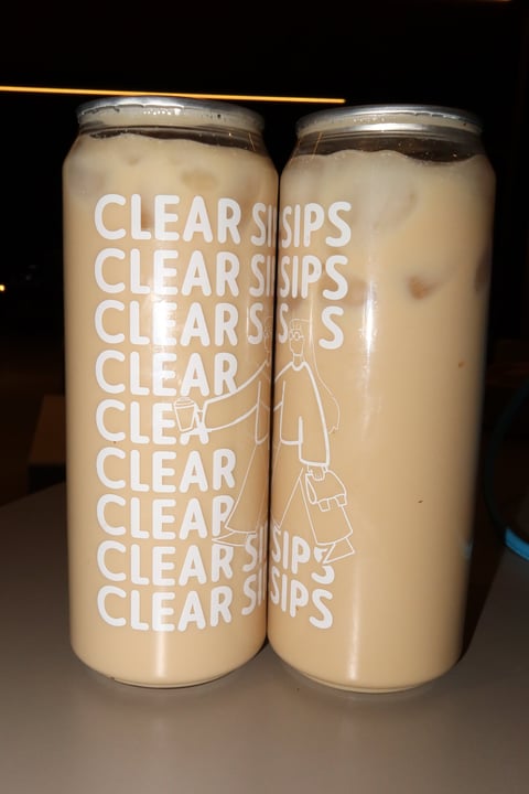 Two tall cans of Clear Sips beverage with white text on beige labels, filled with a light tan-colored drink with ice